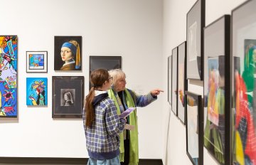 Side view of two people interacting with a framed piece of art in the main gallery