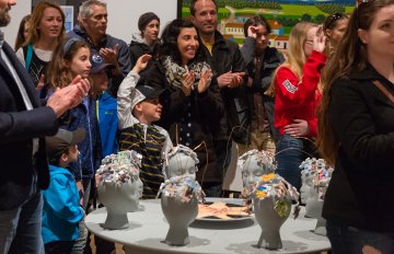 Group of people surrounding students' sculptural work in the youth exhibitoin Expressions