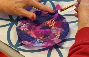 Close-up shot of hands arranging colors on a circular piece of paper