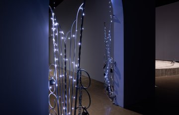 Curved dark, doorway with an onrate gold gate ajar covered in fairylights