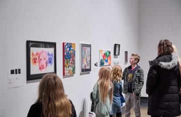 View of a group of people looking at artworks on a white wall