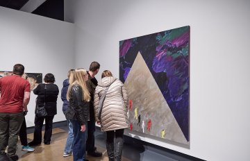 View of a group of people looking at artworks on a white wall