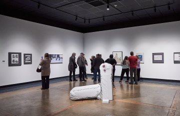 View of a group of people looking at artworks on a white wall