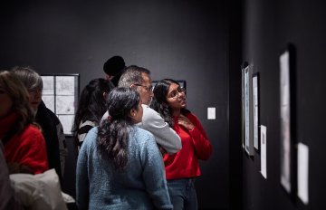 View of a group of people looking at artworks on a white wall