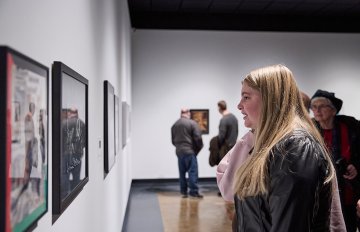 View of a group of people looking at artworks on a white wall
