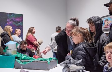 View of a group of people looking at artworks on a white wall