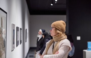 View of a group of people looking at artworks on a white wall