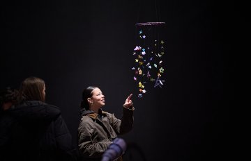 Two people looking up into a hanging display of paper and mixed media stars dangling from above