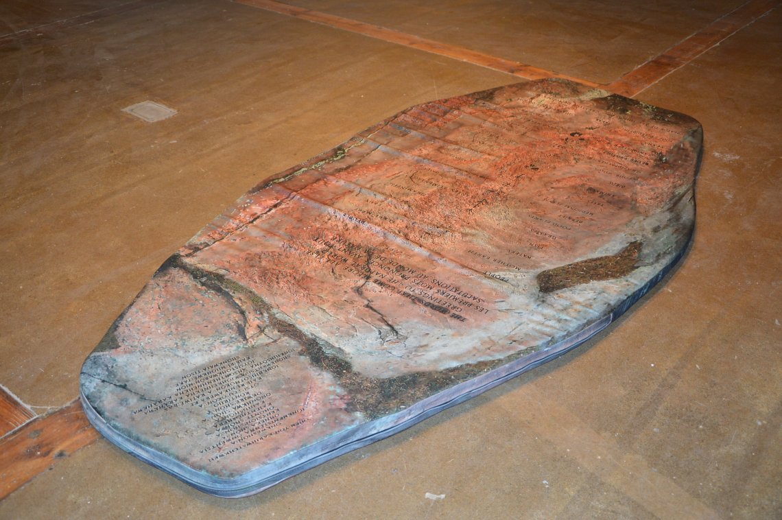 coffin shaped stone on the floor with writing upon it