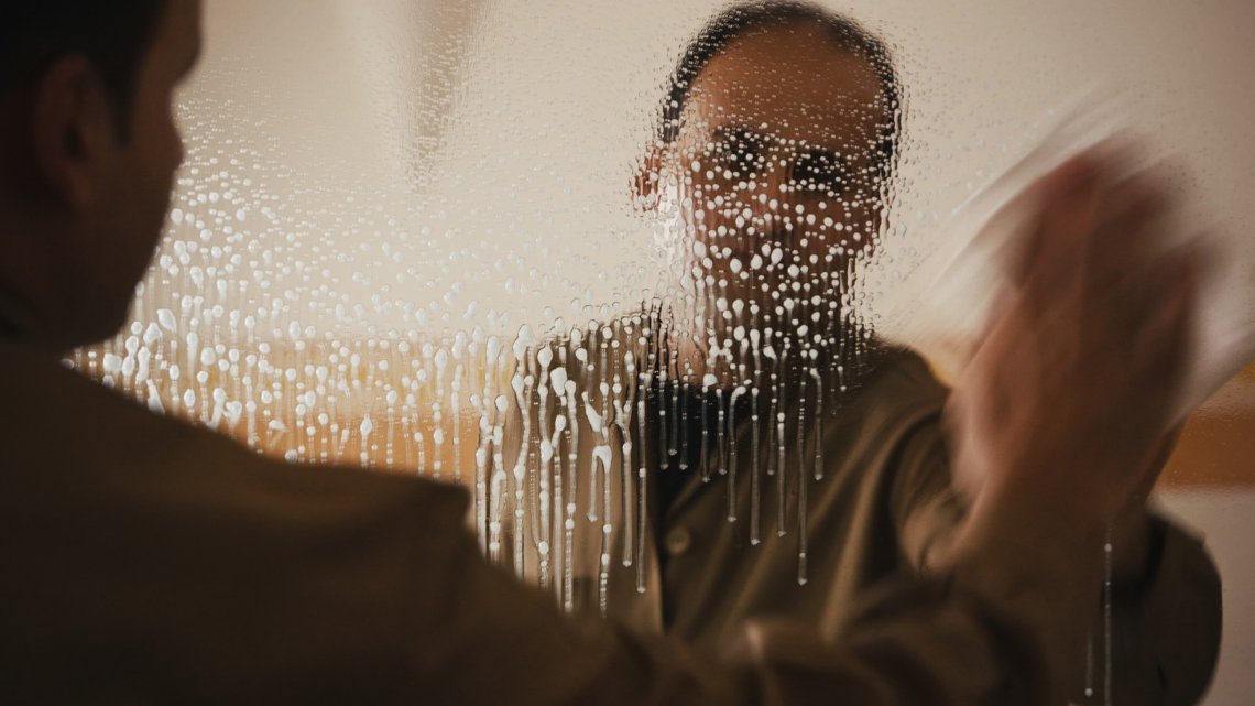 video still of a man cleaning a mirror