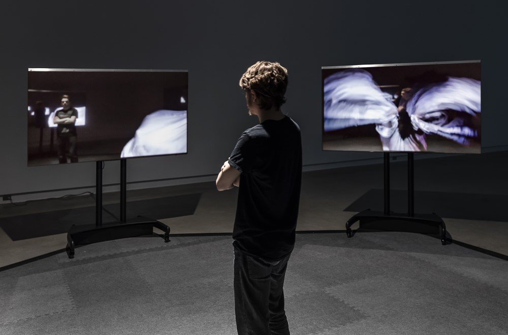 person looking at two tv screens playing imagery across them