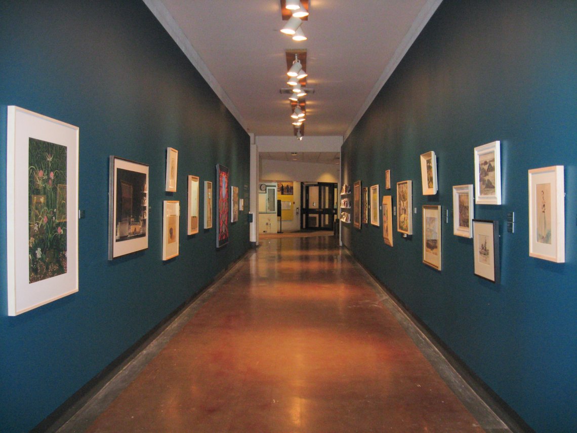 exhibition photo of long corridor with pictures on walls on either side