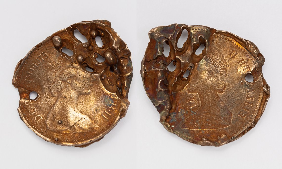 A pair of penny coins that has been mishapen and manipulated to have holes in it