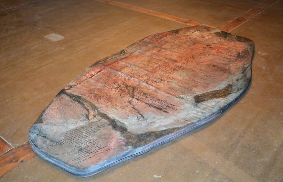 coffin shaped stone on the floor with writing upon it