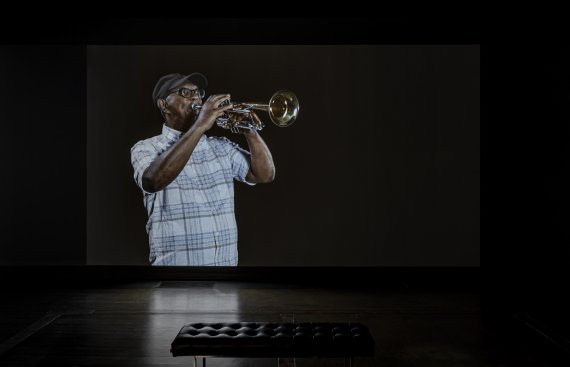 Black man playing trumpet on a large screen