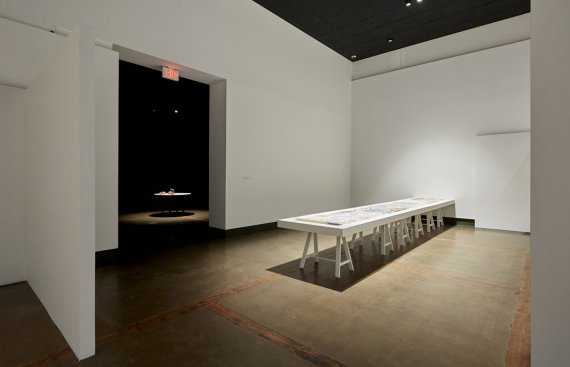 installation shot of exhibition with a long table in the middle