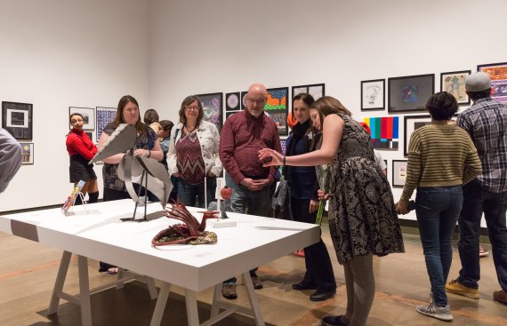 gallery shot of exhibition with people admiring the artwork
