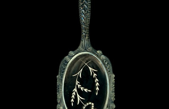 a green hand mirror with flowers painted on the glass