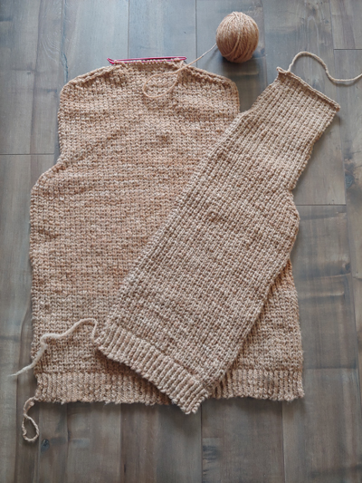 A photo of the back panel of a sweater knitted in warm beige wool