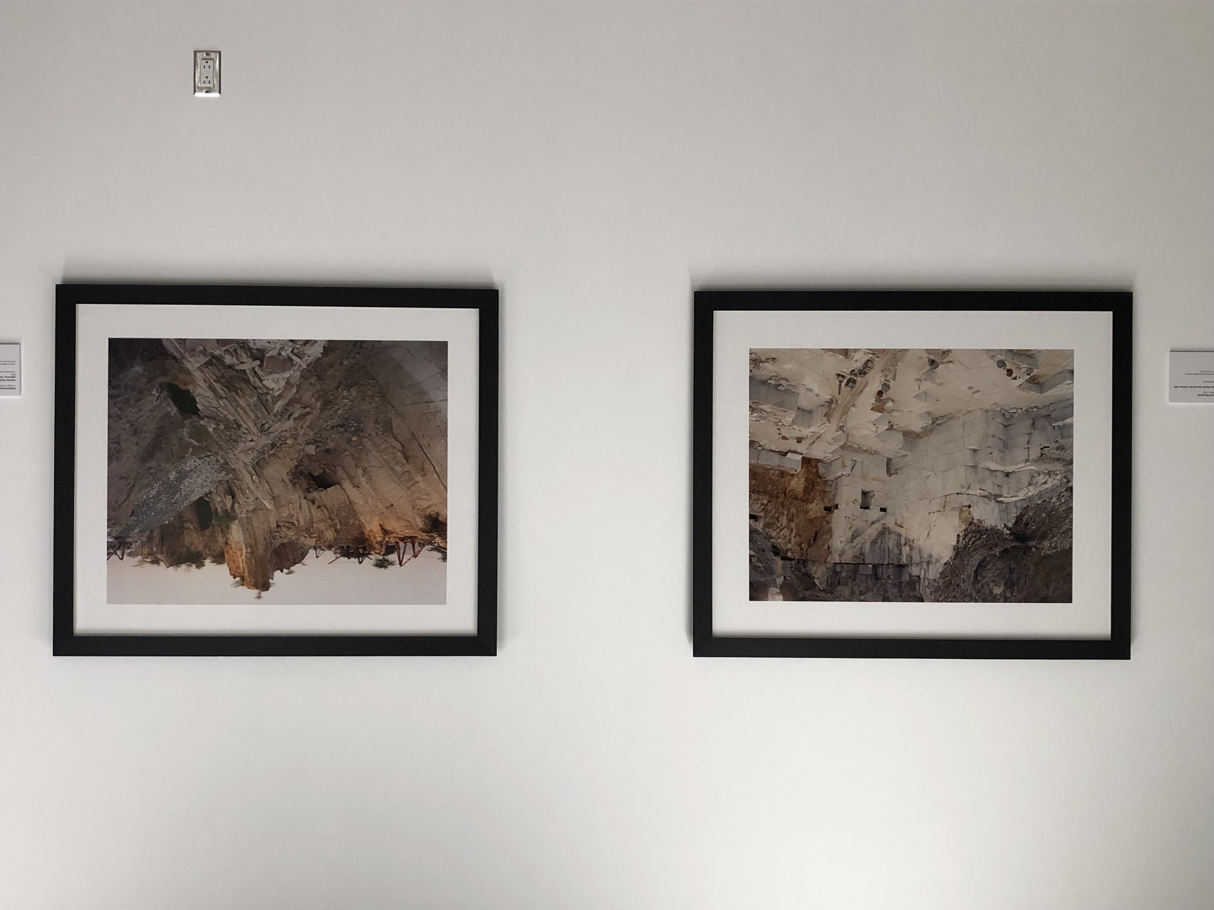 Installation view of two Burtynsky prints of marble quarries in black frames on a white wall