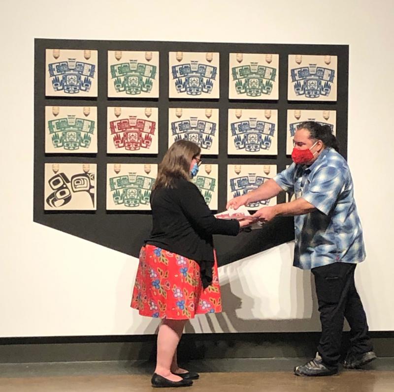 Luke Parnell hands a woman a print from his installation