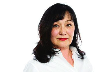 Photo of Shirley Madill, a white woman with shoulder-length black hair wearing a white blouse